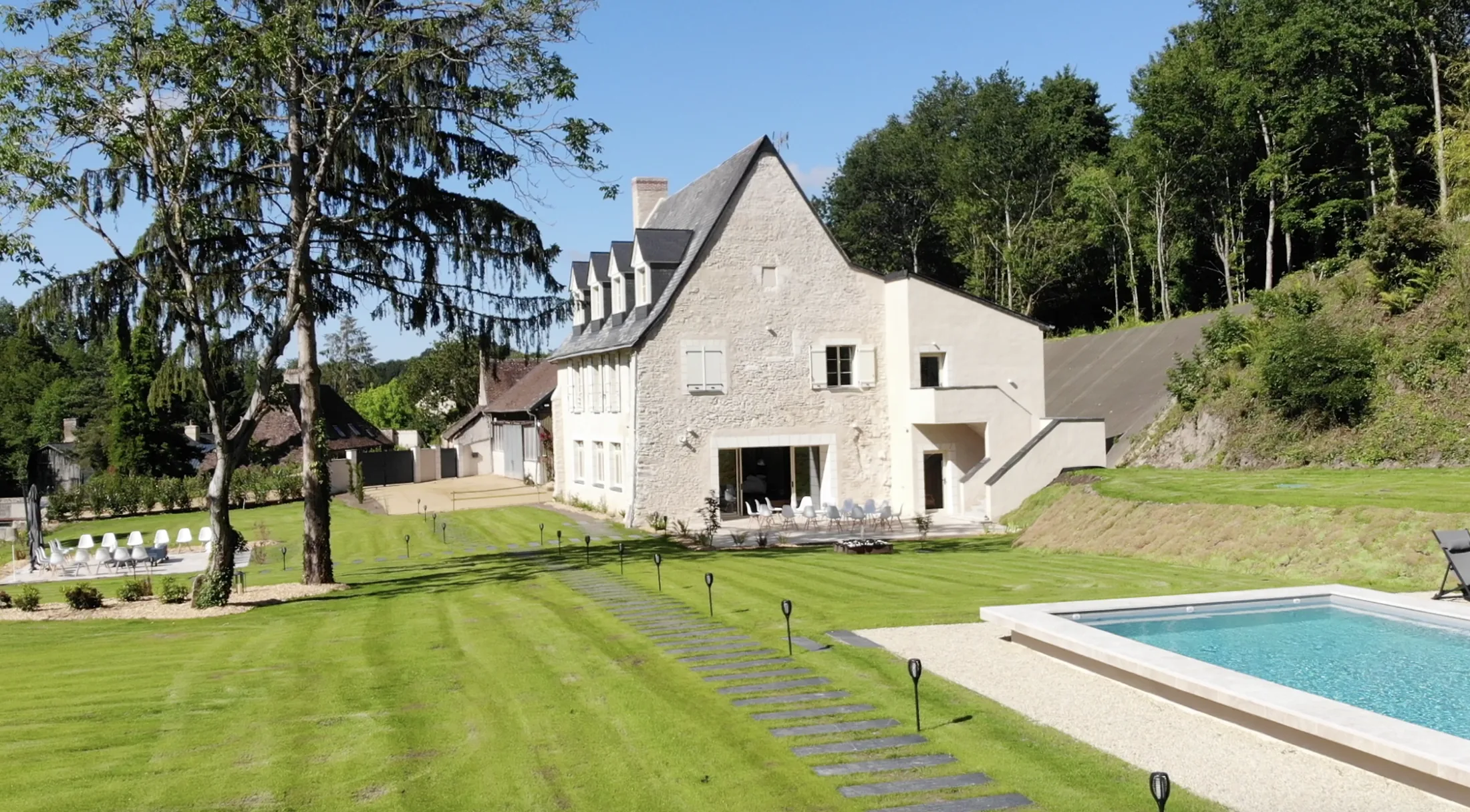 La façade en pierre et la piscine chauffée de La Joyeuse Cousinade